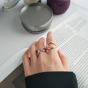 Three minimalist irregular hollow liquid-style rings in silver and gold on model's fingers