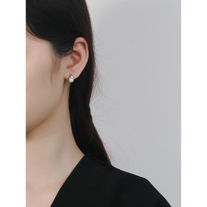 Elegant S925 sterling silver pearl stud earrings worn by a model in a minimalist style