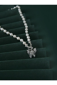 Macro shot of silver butterfly zircon pendant on pearl necklace with unique OT toggle clasp