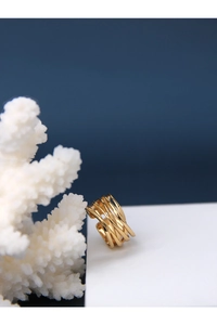 Macro detail of layered wrap gold ring with textured lines on a white stand