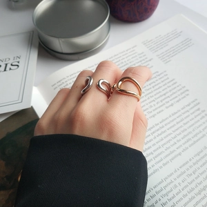 Detail shot of wavy minimalist silver and gold rings worn together on fingers
