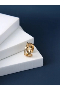 Close-up of golden multi-layer crisscross ring on white podium with blue background
