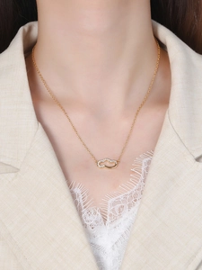 Close-up of gold cloud pendant necklace with white zircons on model with cream blazer