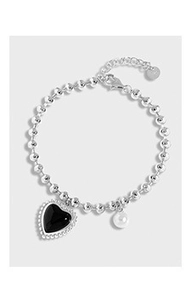Detail view of silver beaded necklace with black heart pendant and pearl accent