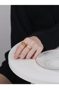 Close-up of a stacked 18K gold-plated twist band and a large rectangular zircon ring