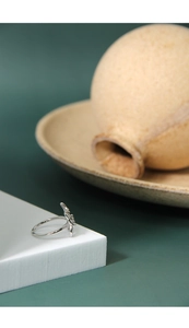 Macro detail of S925 sterling silver butterfly ring on minimalist ceramic decor