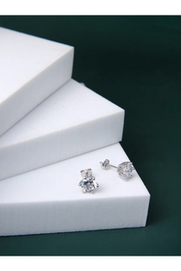Détail de boucles d'oreilles en argent avec zircone à six griffes sur bloc blanc