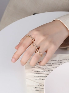 Gros plan d'une bague chaîne dorée sertie de zircons portée par un mannequin chic