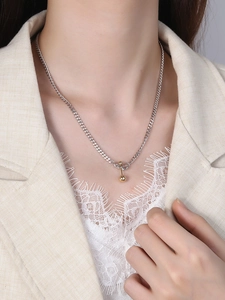 Close-up of a S925 sterling silver minimalist necklace with a golden balance ball pendant