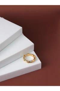 Macro view of gold-plated silver ring with wavy organic texture on white stands