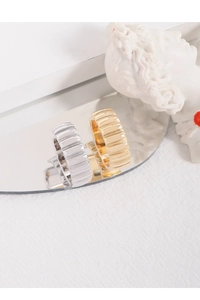 Detailed view of gold and silver textured metal earrings on a mirror surface