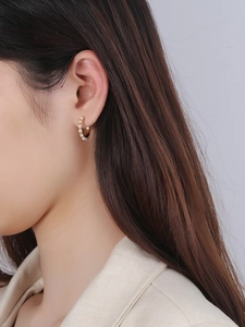 Close-up of elegant gold hoop earrings featuring a ring of white pearls on female model