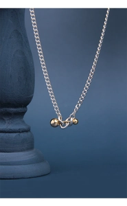 Detailed macro of S925 silver Cuban chain necklace with gold ball pendant accents