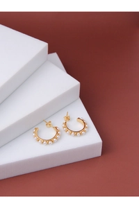 Detail of gold C-shaped hoop earrings with small white pearls on geometric blocks