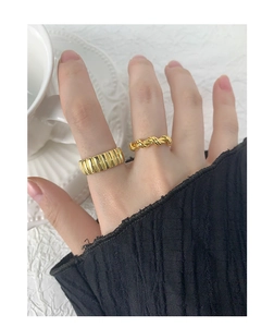 Close-up of golden gear-textured and twisted rope rings on fingers in a minimalist style