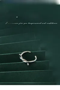 Macro di ear cuff a nodo d'argento su sfondo di carta verde scuro dallo stile premium