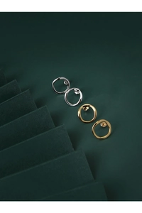 Detail of irregular round stud earrings in silver and gold with lava texture finish