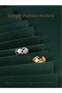 Detailed view of silver and gold geometric quilted pattern rings on a paper stand