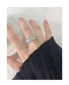 Close-up of silver gear-style textured ring with vertical ridges on a model's hand