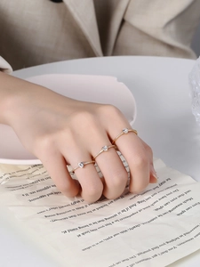Set di tre anelli dorati con zirconi a cuore indossati da una modella con eleganza