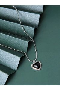 Detailed macro shot of silver bead chain necklace with a black heart pendant on dark background