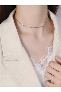 Detail shot of dainty gold pig-nose chain necklace on a model wearing a lace blouse