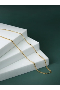 Close-up of interlocking gold oval links necklace displayed on white tiered blocks