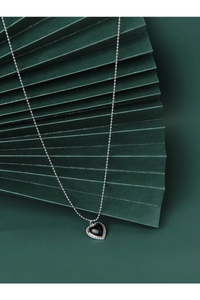 Detail view of heart-shaped black onyx pendant with silver beaded edges and ball chain necklace