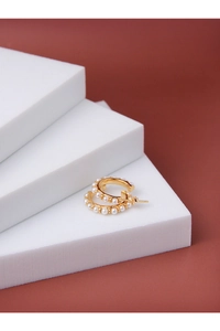 Detail of C-shaped gold hoop earrings with white shell pearls on a geometric block