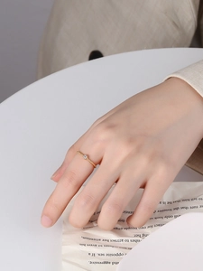 Close-up of thin gold twisted rope ring with a sparkling round zircon on finger