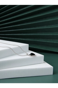 Detail of silver beaded chain necklace featuring black heart onyx pendant and beaded trim