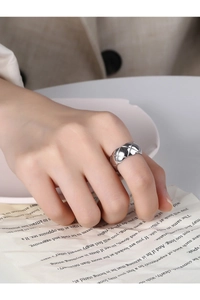 Close-up of a silver quilted pattern ring on a finger with an elegant lifestyle setting