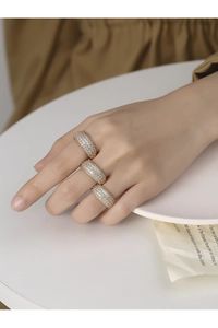 Close-up of wide gold-plated rings with paved white zircons worn on model fingers