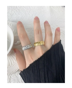 Detail of silver and gold gear-style rings with vertical striped textures on model