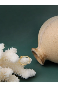 Artistic detail of a minimalist 18K gold beaded open ring on a white coral stand