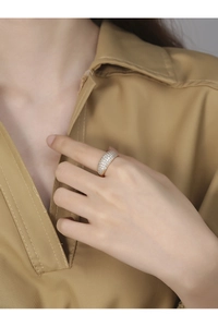 Detailed view of a wide gold ring with micro-pave zircon crystals on a female finger