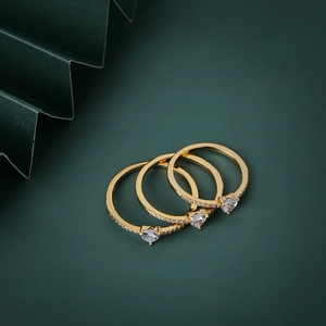Set di tre eleganti anelli d'oro con zirconi a forma di cuore su sfondo verde scuro