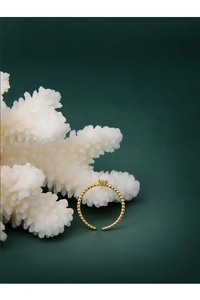 Detailed close-up of golden beaded adjustable ring with crown motif on coral decor