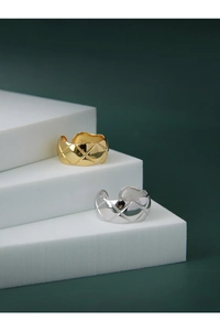 Macro detail of gold and silver quilted motif rings on geometric display steps
