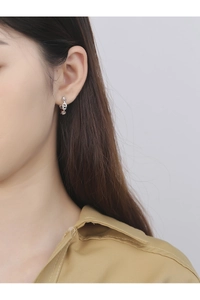 Close-up of minimalist silver pig-nose anchor chain hoop earrings on female model's ear