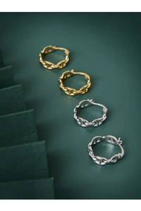 Macro detail of gold and silver anchor link hoop earrings on a dark green surface