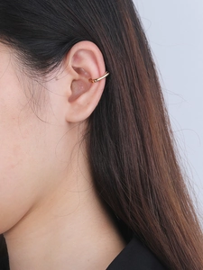 Vue détaillée d'un ear cuff doré irrégulier avec zircon sur l'oreille d'un modèle