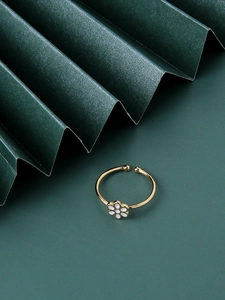 Macro shot of gold-plated daisy enamel flower ring on creative green paper background