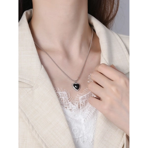 Minimalist black heart pendant necklace with silver beaded trim on elegant model