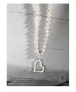 Macro detail of textured hollow heart pendant on natural freshwater pearl necklace