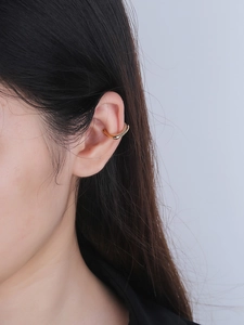 Gros plan d'une manchette d'oreille ondulée dorée à double couche sertie de zircons