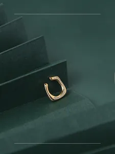 Détail macro d'un earcuff doré en forme de U avec pierres de zircone incrustées