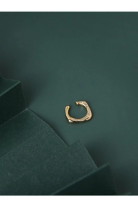 Gros plan détaillé d'un earcuff doré ondulé serti de micro-pave de zircons brillants