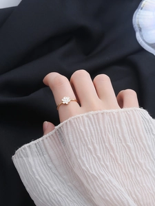 Macro view of gold S925 silver ring featuring a delicate white enamel flower on the finger