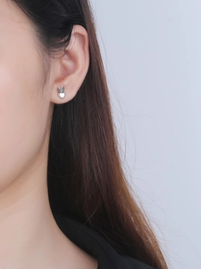 Detail of S925 sterling silver heart crown stud earring worn by a model on a gray background